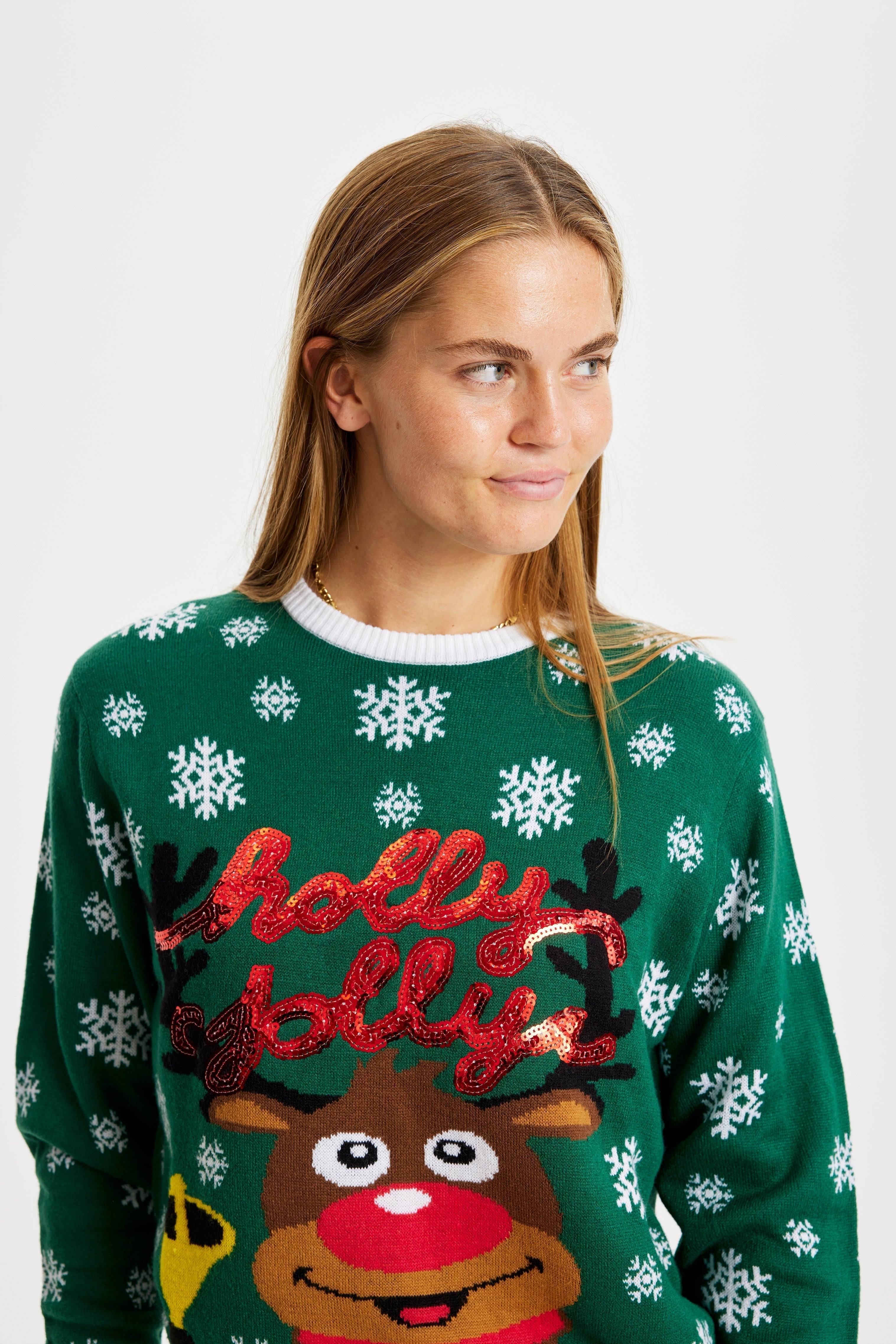 Una donna sorridente posa indossando un maglione natalizio verde.